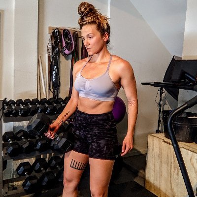 A woman in a fitness photo with dumbbells in the background