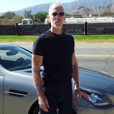 P.D. Mangan in a black tee in front of a car