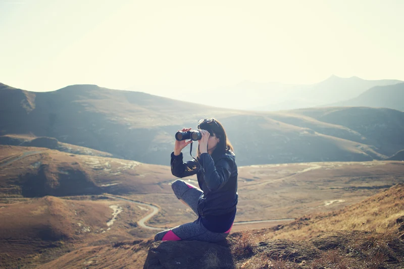 A woman has binoculars in a field